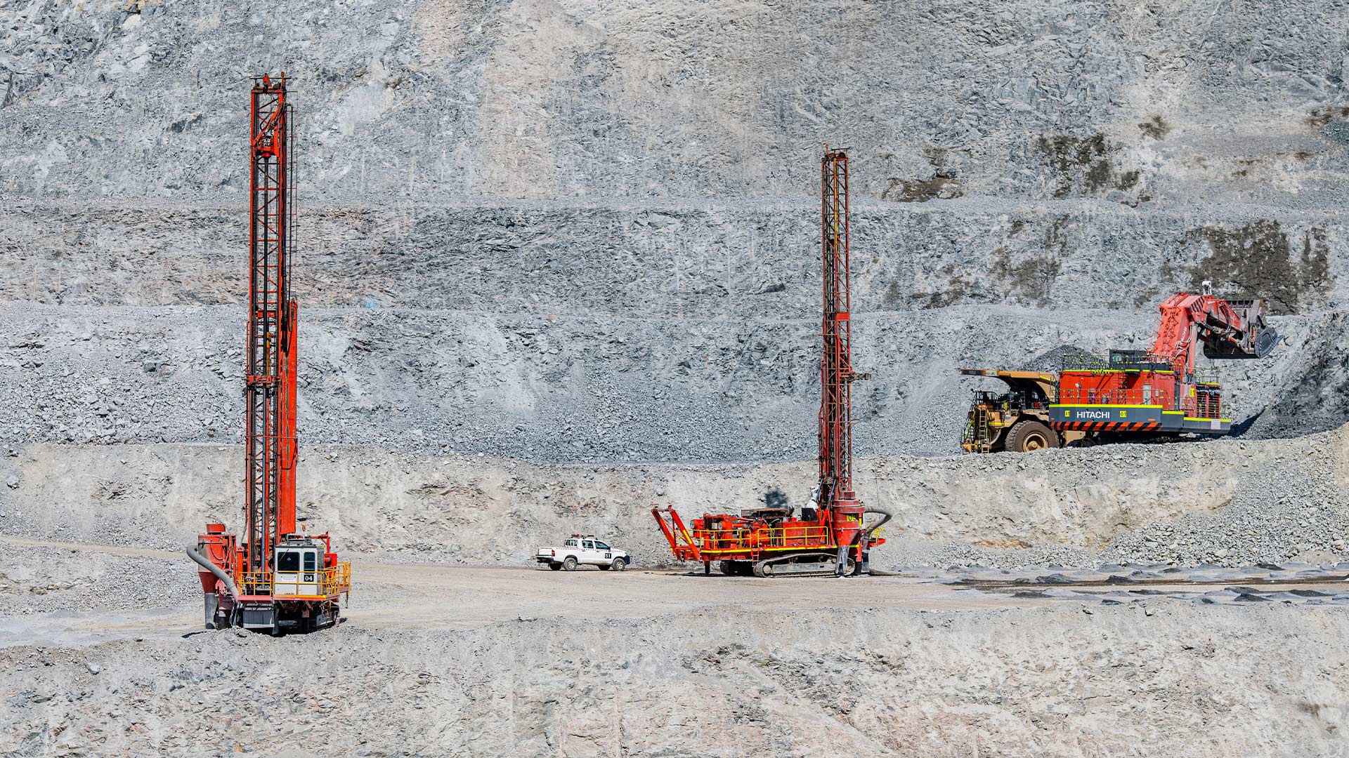 Mining machinery set against large rocky environment. 