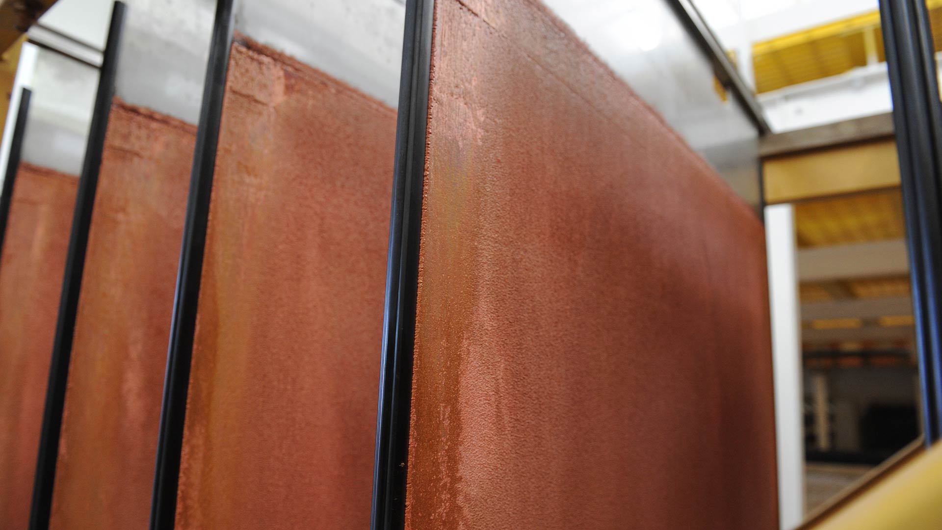 Side view image of four copper sheets hung consecutively in a row. 