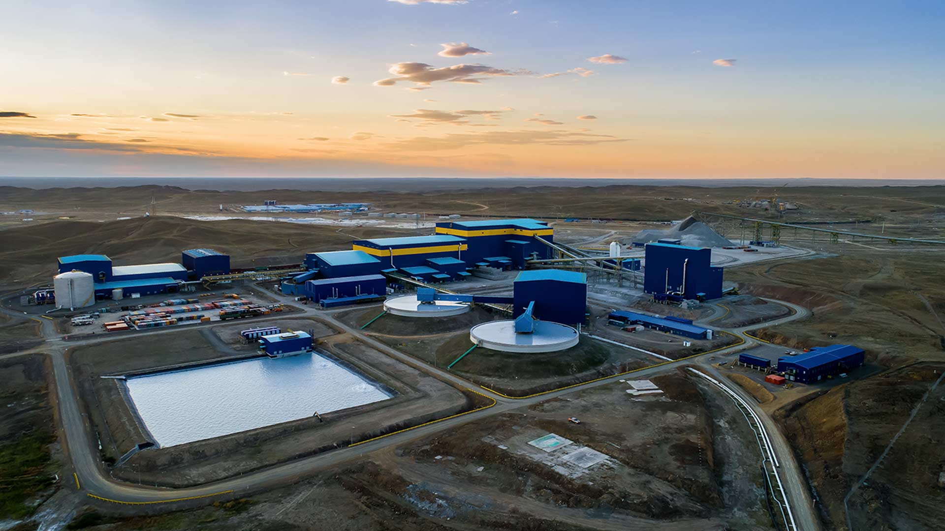 A pastel gradient sky seen in the distance. From an elevated drone view, multiple facilities are visible. 