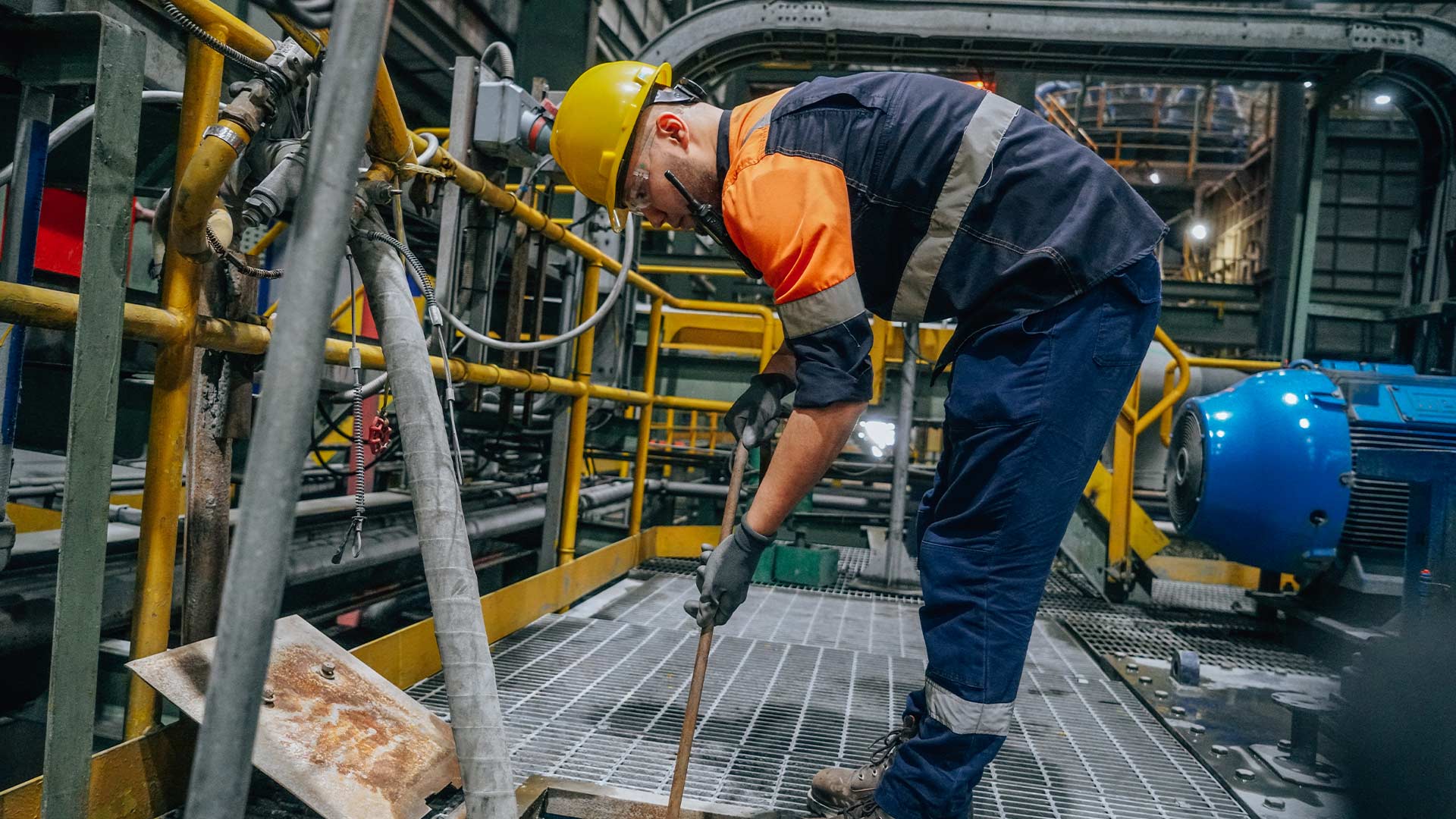 Worker in safety clothing, headgear and goggles in copper facilities working with the material. 