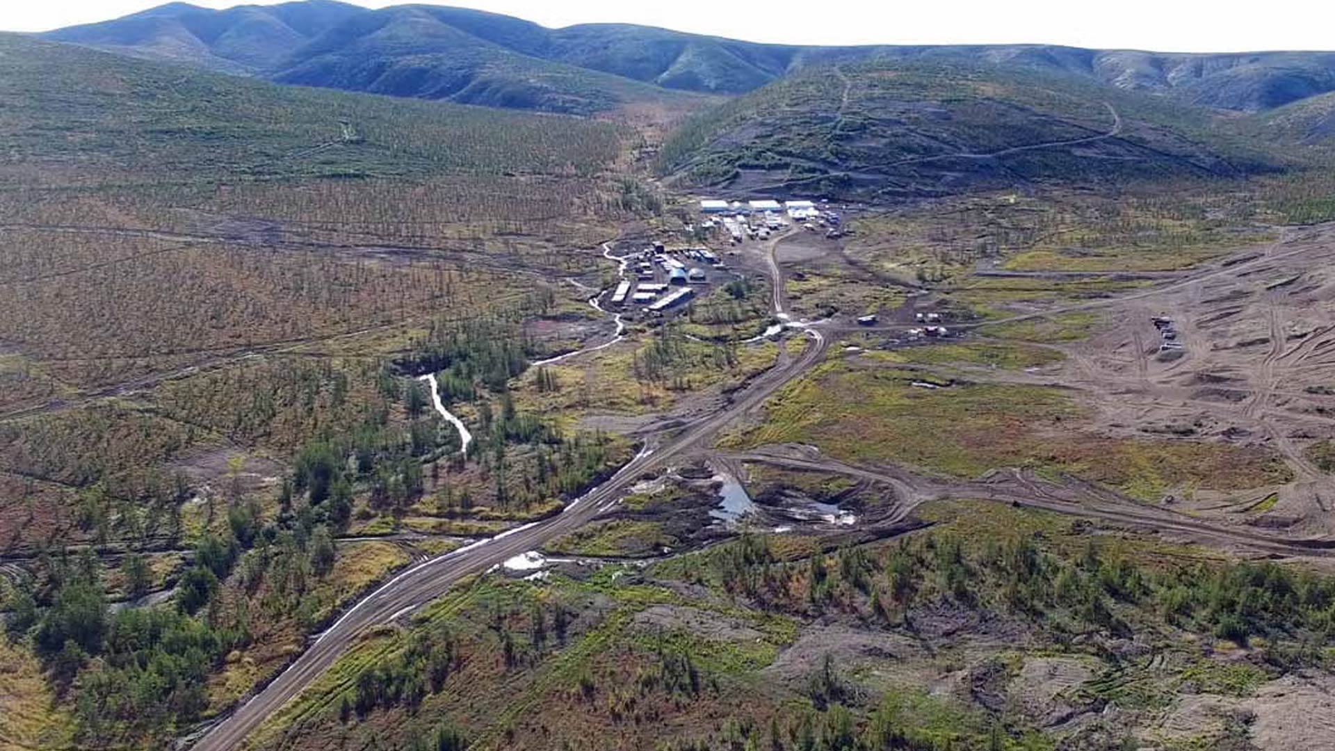 Large open area of grasslands, hills, and mountains in the distance. 